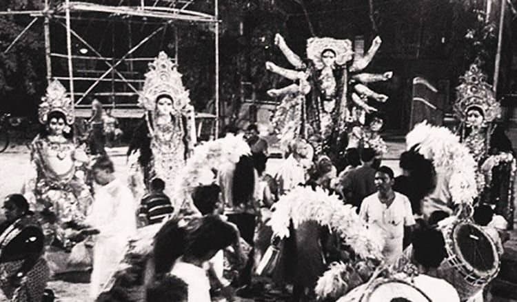 The pratima in its arch with a crowd pressed to the rail