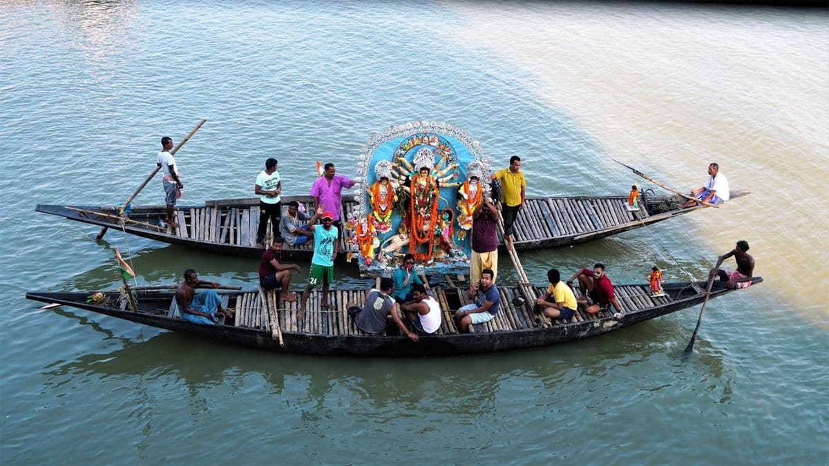 Three country boats lashed together carry a Durga in white pith ornament down the Ichamati at Taki on Bijoya Dashami.