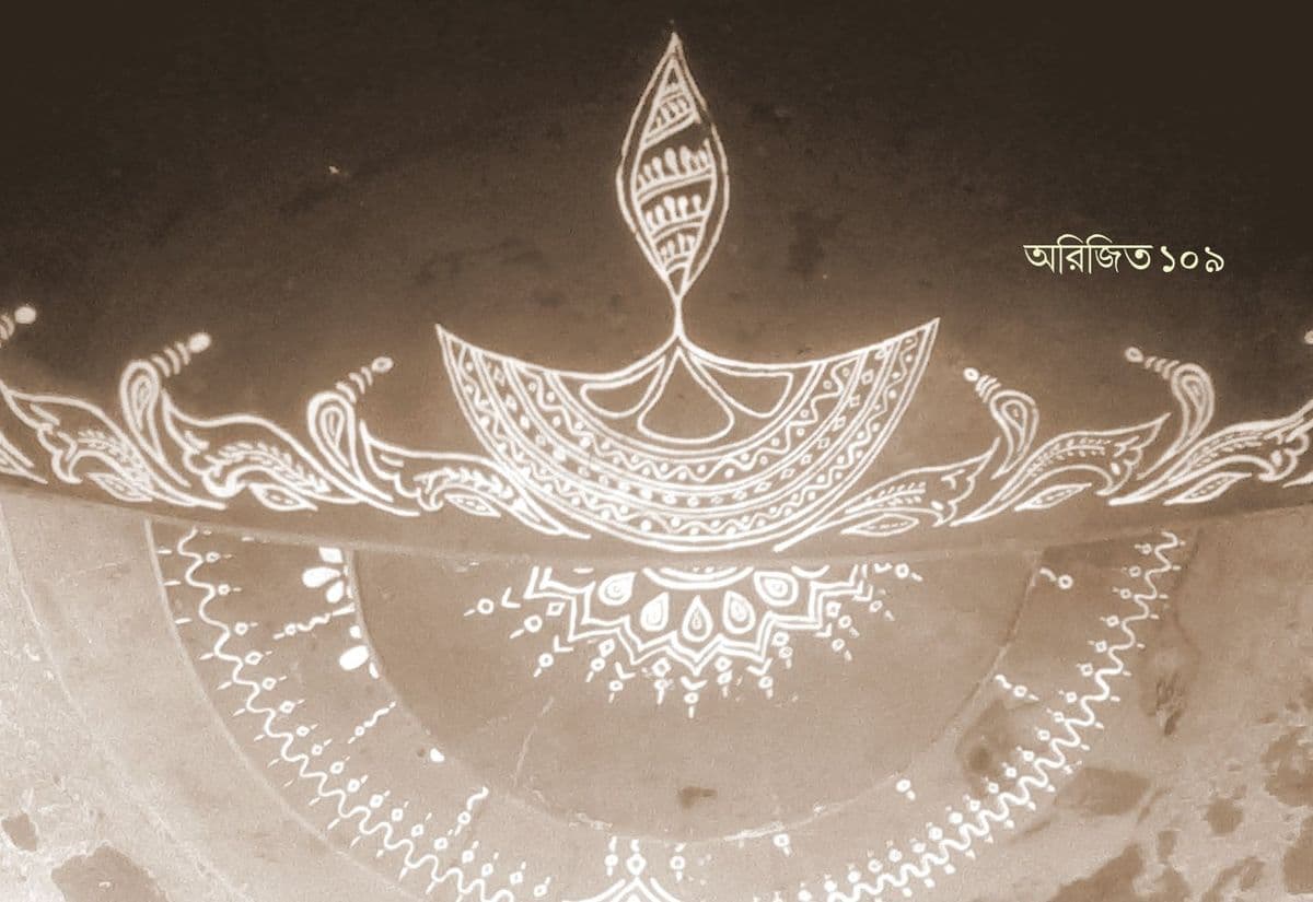 A rice-paste alpona of a lamp flame above a scalloped bowl, bordered by fine dotted and scrolled bands.