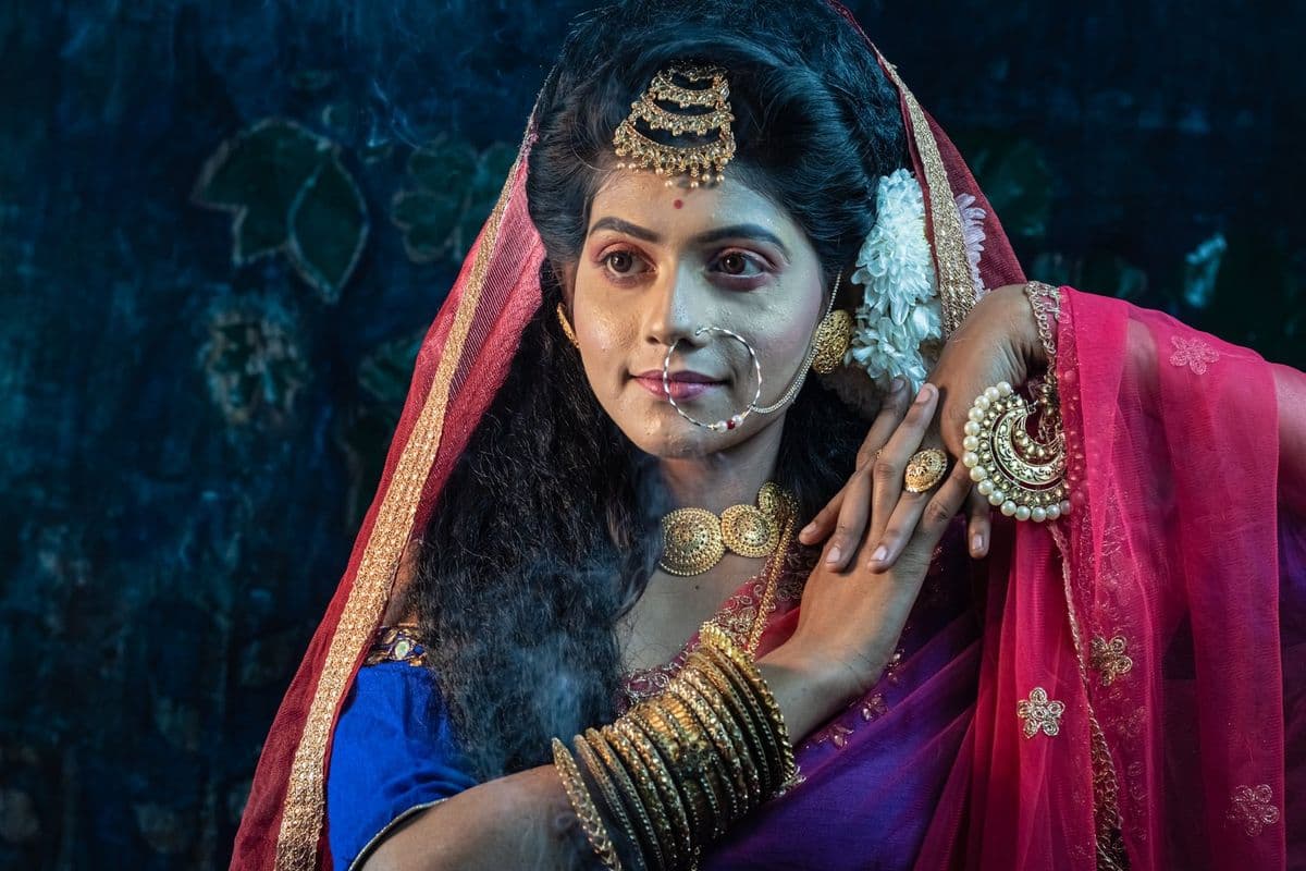 Makeup before an outdoor jatra: heavy and emblematic rather than realistic, applied in the open behind the stage.