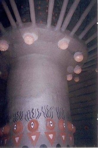 Inside a Kolkata pandal in 2005: a tapering bamboo-framed column hung with lamps and painted with folk motifs around its base.