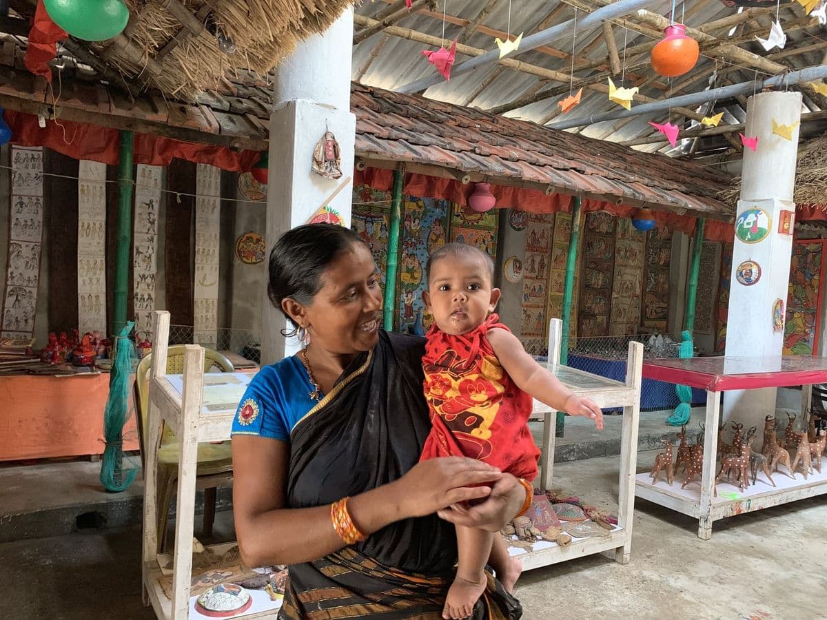 The patua Nadira Chitrakar with her child in a Pingla house whose walls and pillars are covered in pata work.