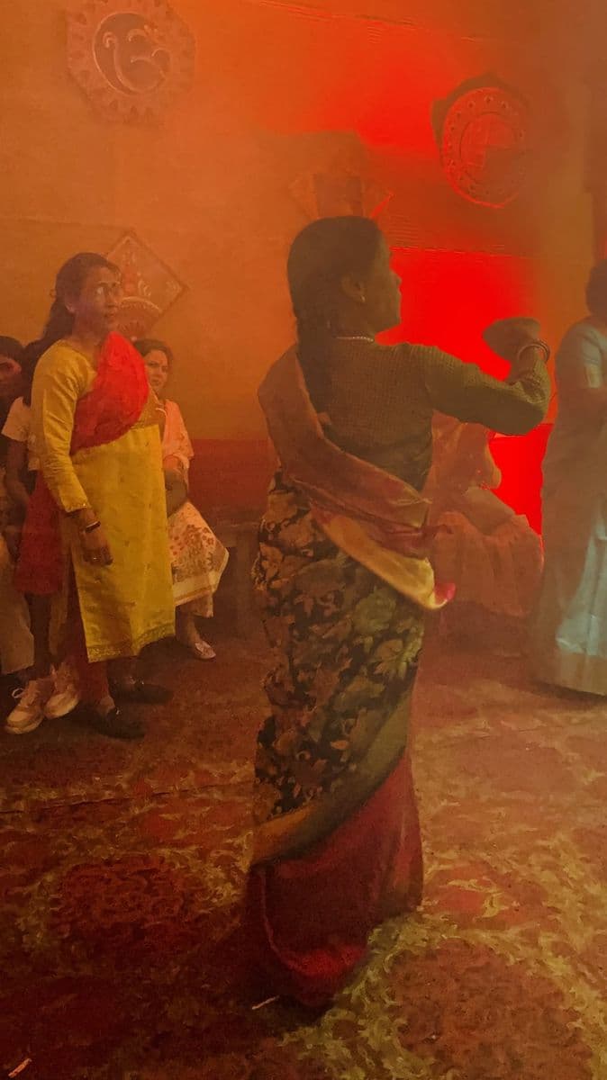 A woman in a sari dances with a dhunuchi in red-lit smoke at a Durga Puja in Dibrugarh, Assam.